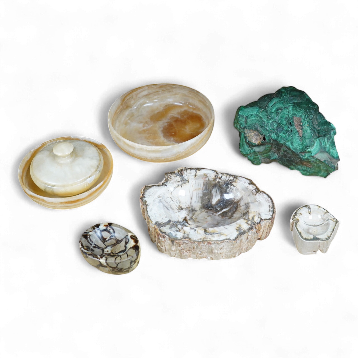 Two petrified wood ashtrays, a malachite rock, three onyx bowls, one with cover, and one other item, larger ashtray 17.5cm wide